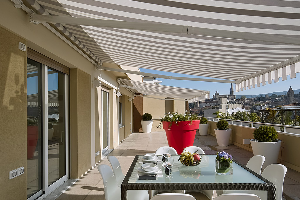 exteriors shots with the foreground glass dining table with plates and a bunch of grapes awning installation