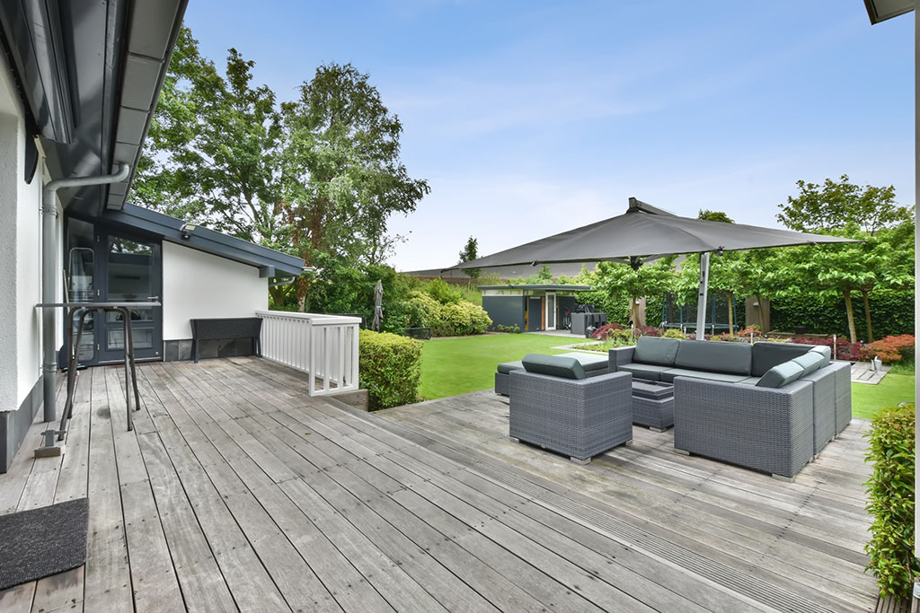 Small sitting area under a canopy on a wooden floor in the backyard of a modern house